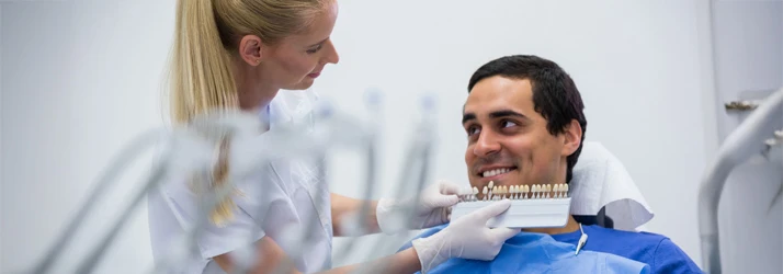 Periodontist Portland ME Female Dentist Examining Patient and Comparing Teeth Shades Cosmetic Focused Female Dentist Examining Patient and Comparing Teeth Shades